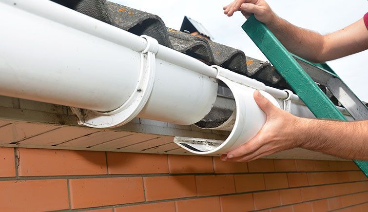 A person is installing a gutter on the roof of a house.