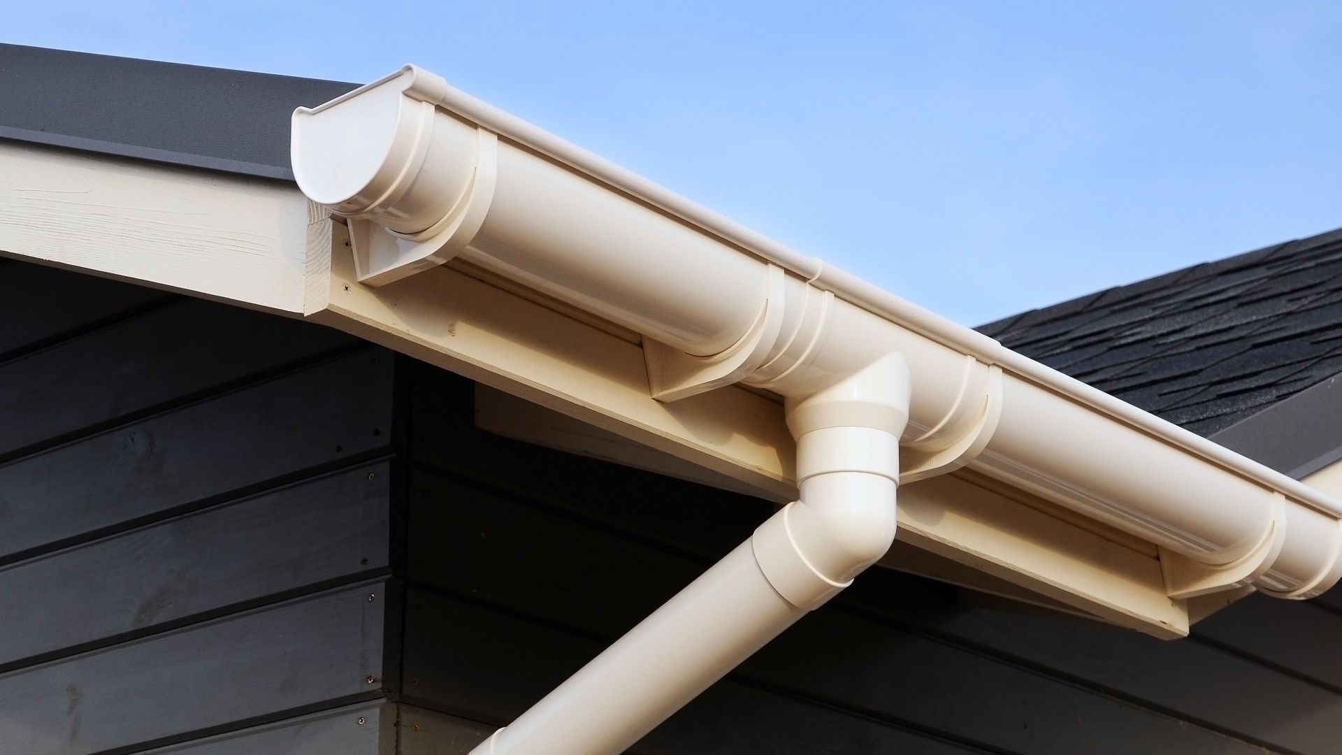 A close up of a white gutter on the side of a house