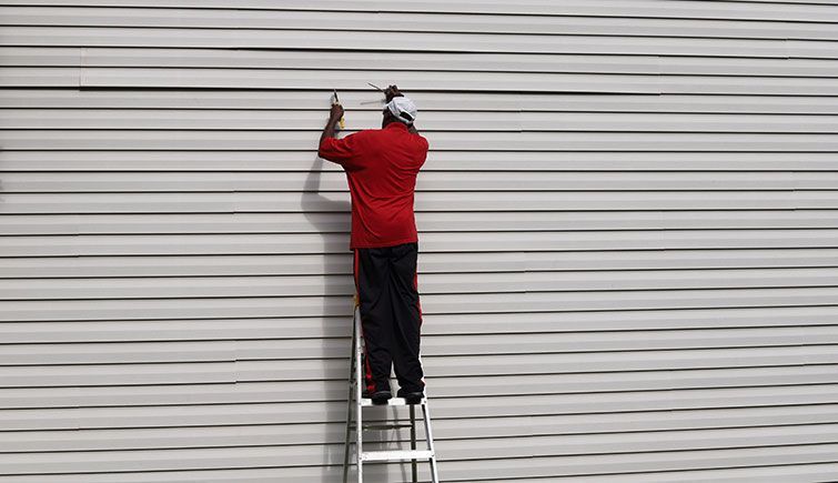 A man is standing on a ladder against a white wall.