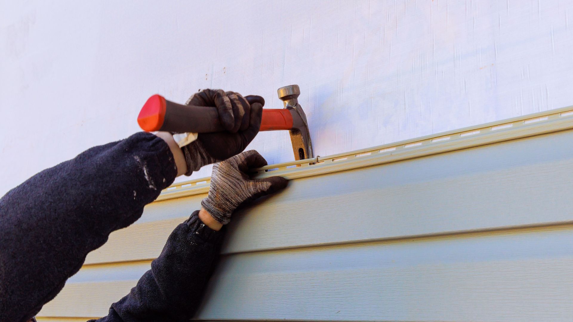 A person is hammering a nail into a wall.