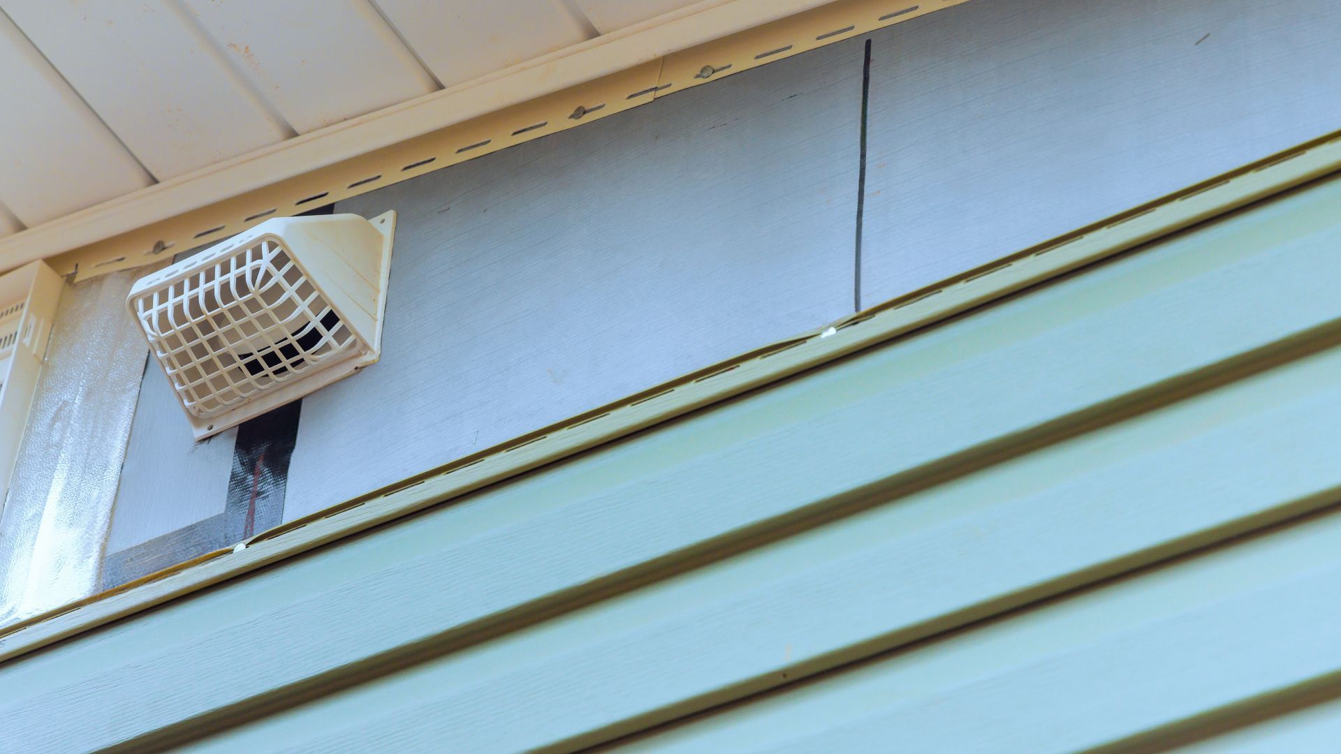 A fan is hanging from the side of a house.