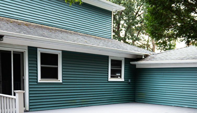 A blue house with a garage and a patio in front of it.