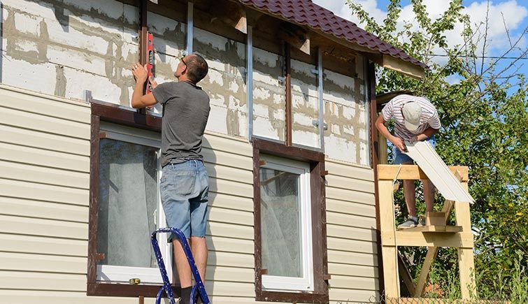 Two men are working on the side of a house.