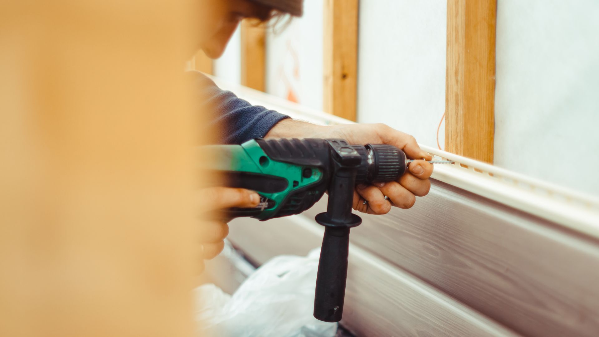 A man is using a drill to drill a hole in a wall.