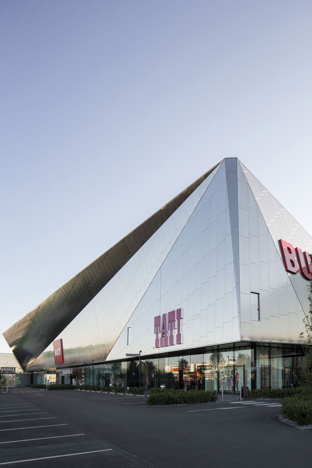 Façade de magasin moderne avec miroirs et enseigne rouge « Bauhaus ».