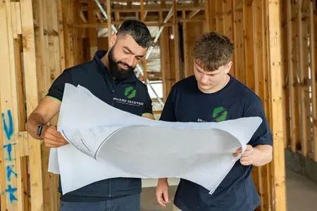 Two men are looking at a blueprint in a building under construction.