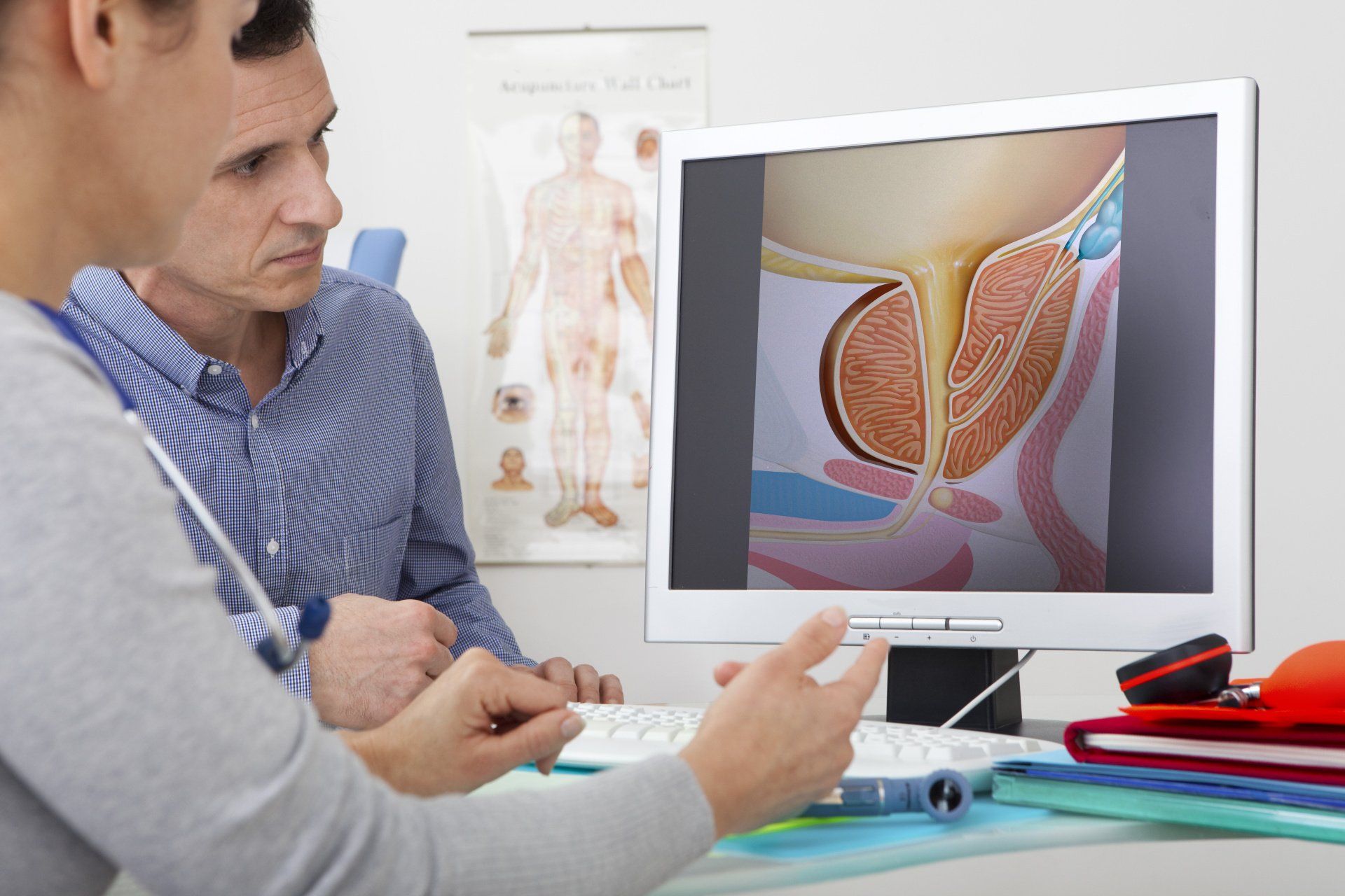 Doctor and patient looking at a cross-section diagram of a prostate on a computer screen in an office.