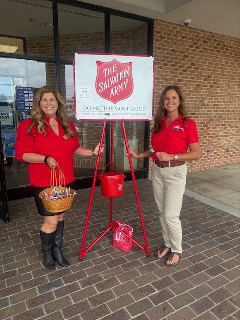 Two women are standing in front of a salvation army sign.