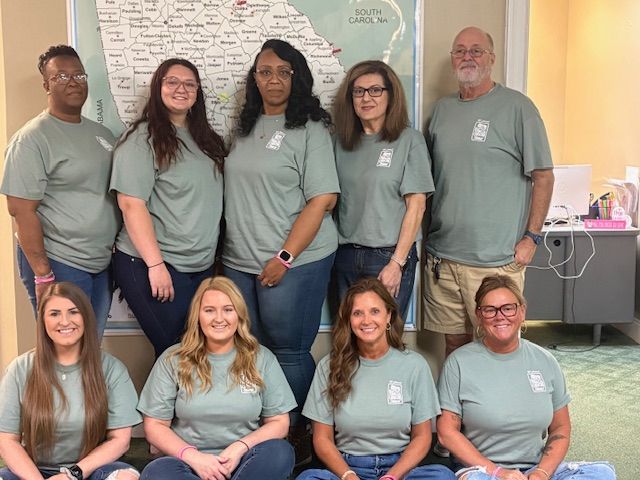 A group of people wearing green shirts are posing for a picture.