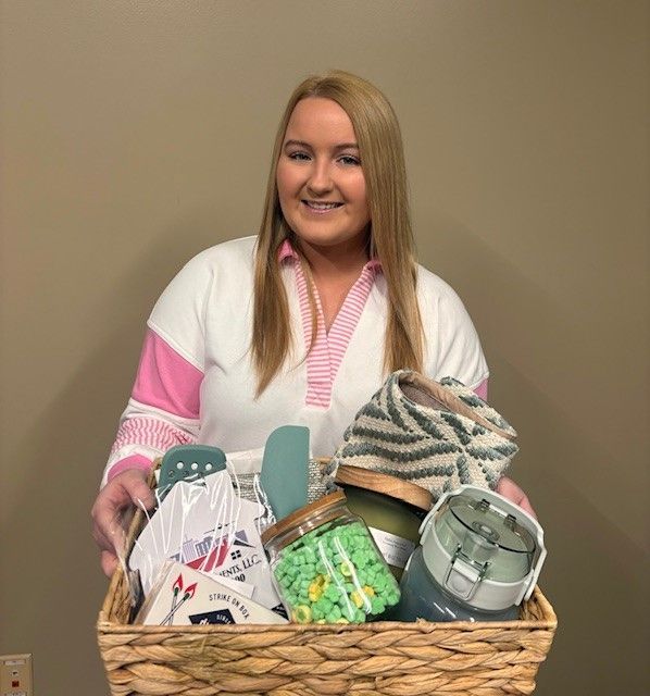 A woman is holding a basket filled with various items.