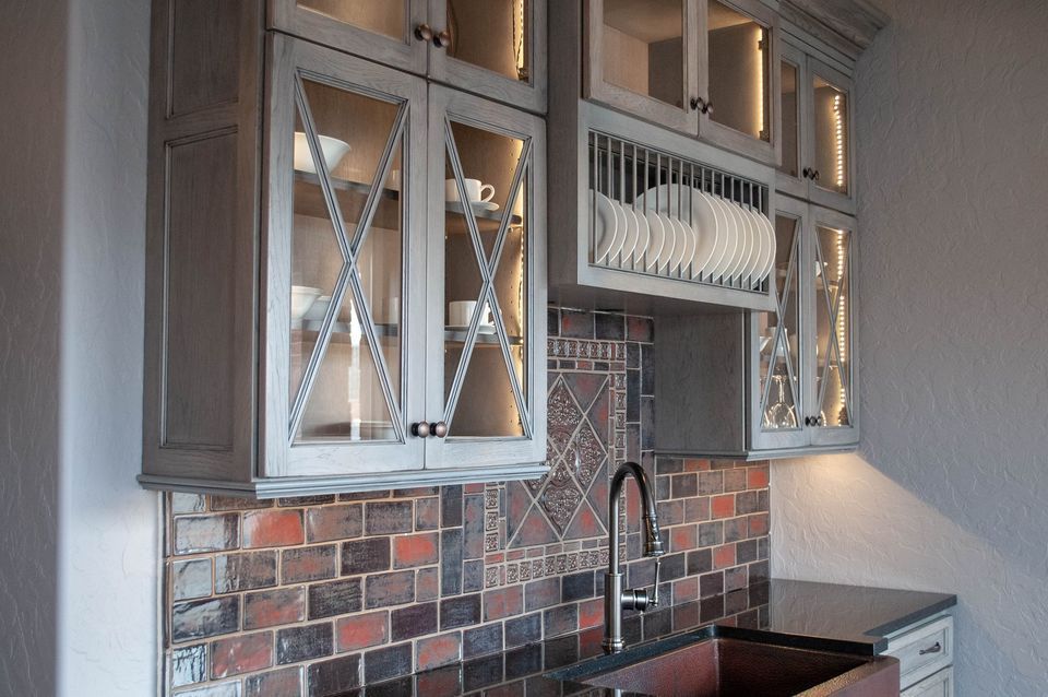 A kitchen with a sink , cabinets , and a brick wall.