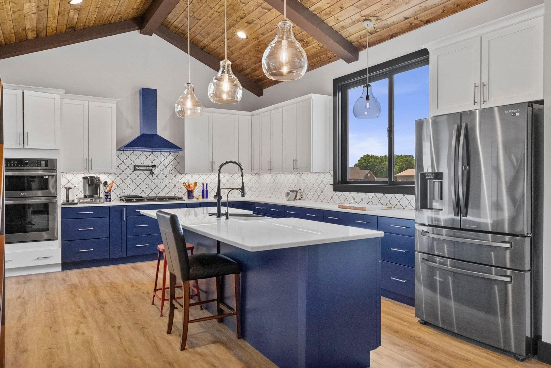 A kitchen with blue cabinets , white cabinets , stainless steel appliances and a large island.