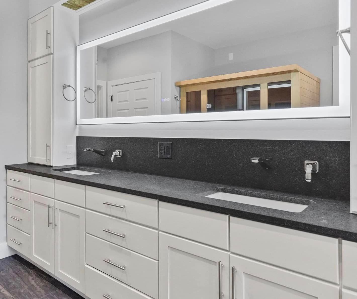A kitchen with white cabinets and black counter tops