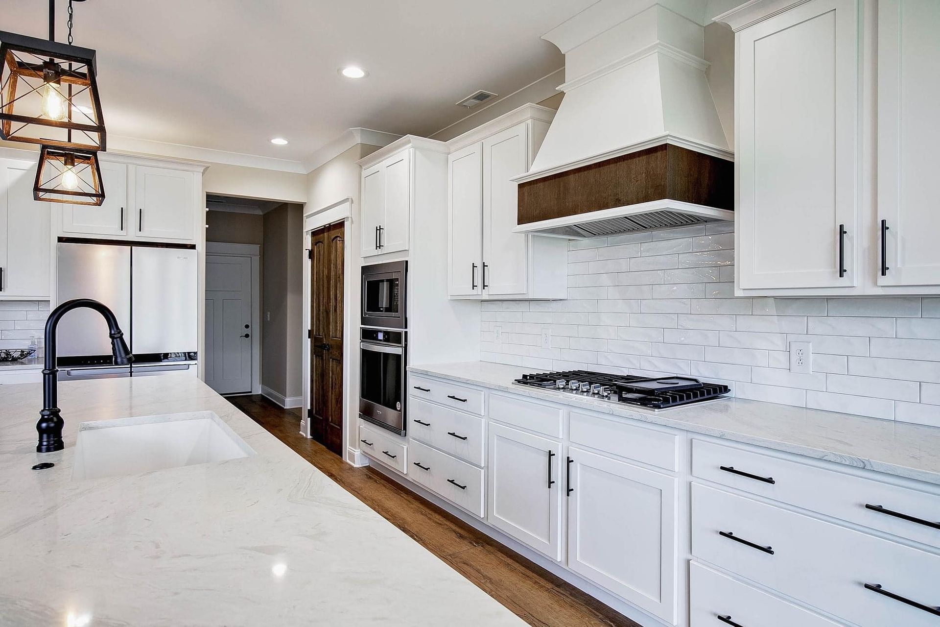 A kitchen with white cabinets , stainless steel appliances , a sink , and a stove.