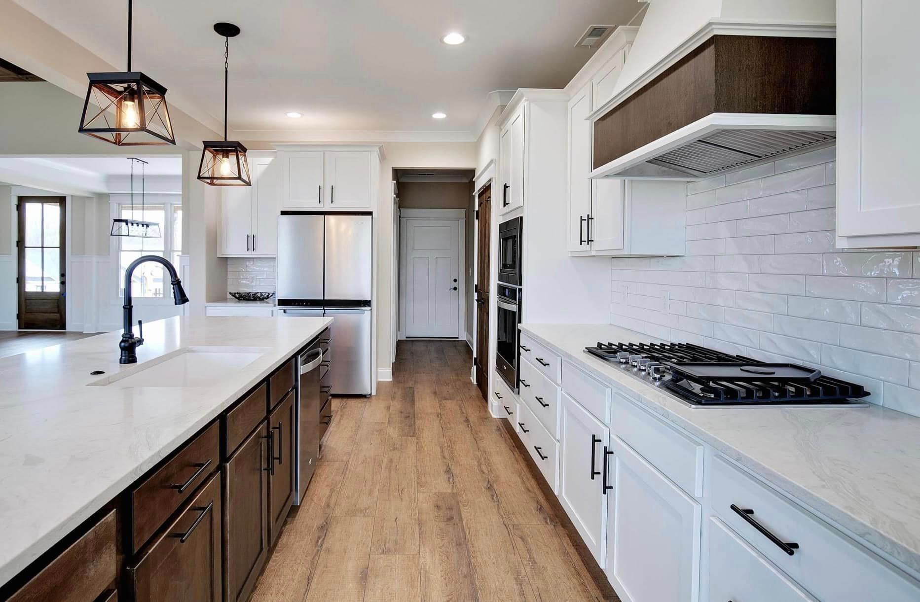 A kitchen with white cabinets and wooden floors and a stove top oven.
