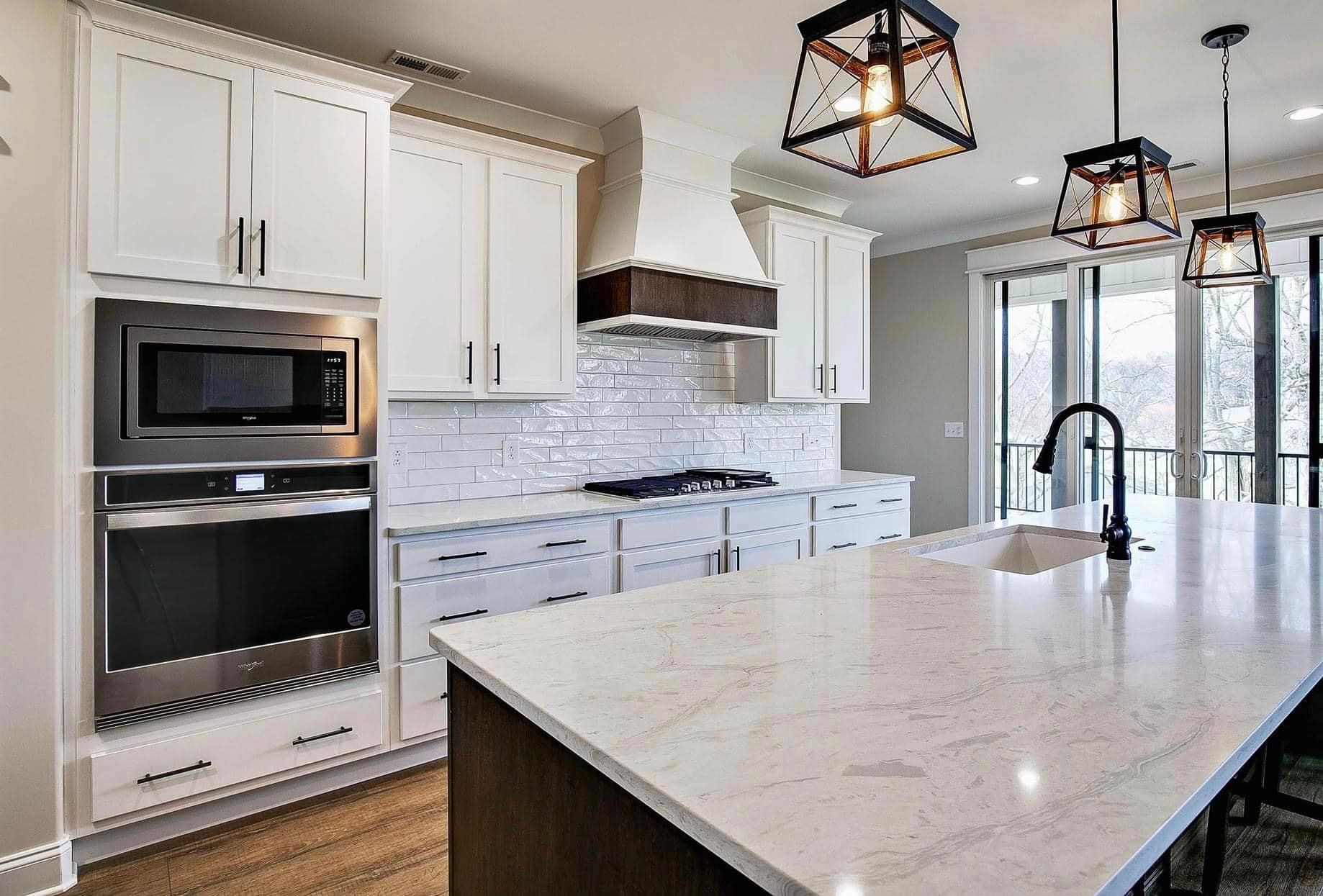 A kitchen with white cabinets , stainless steel appliances , and a large island.