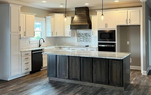 A kitchen with white cabinets and a large island in the middle.