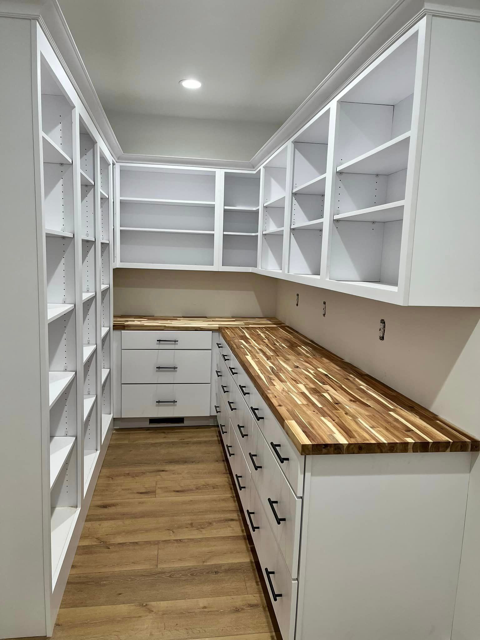 A kitchen with white cabinets and a wooden counter top.