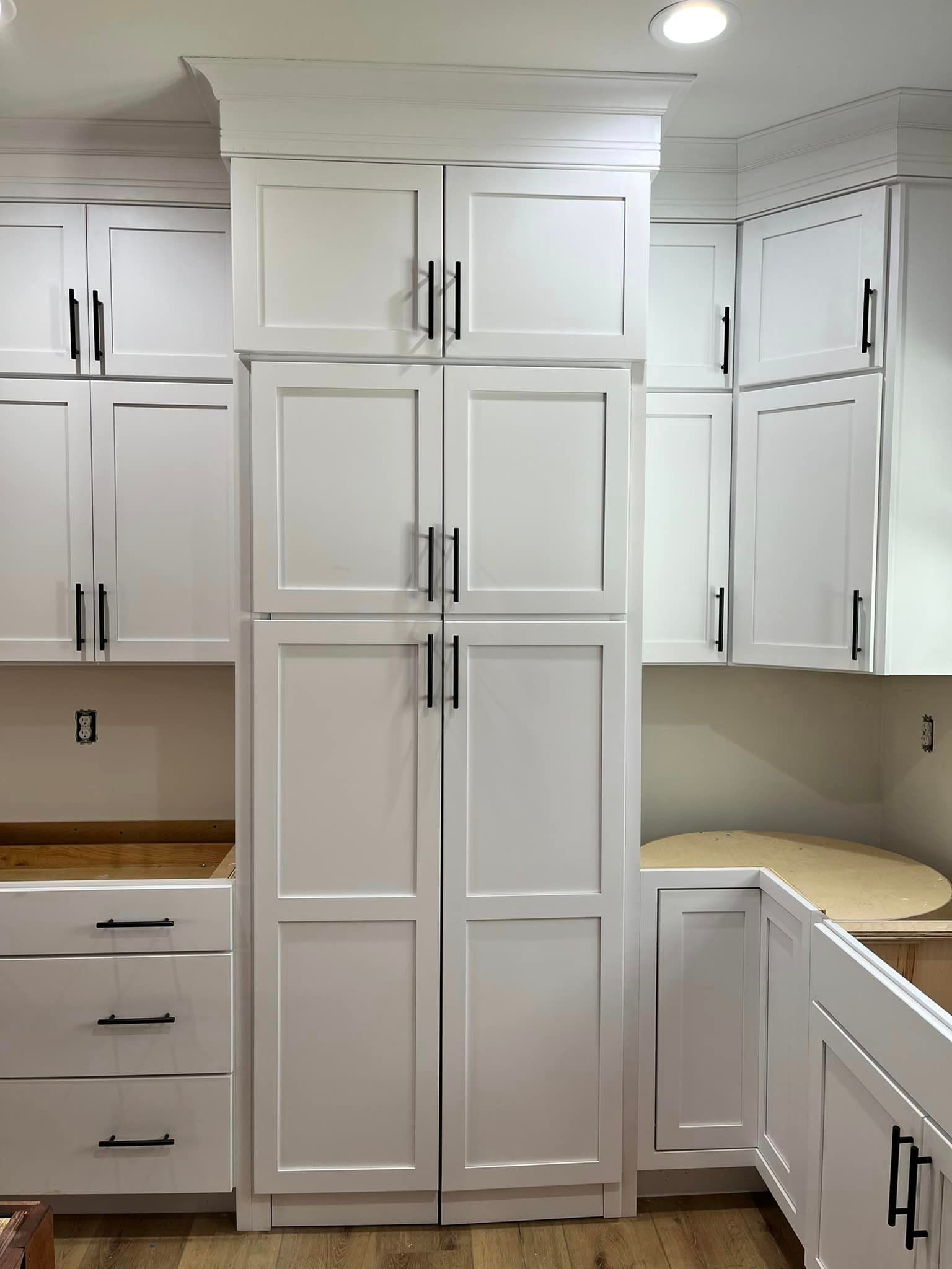 A kitchen with white cabinets , drawers , and a refrigerator.