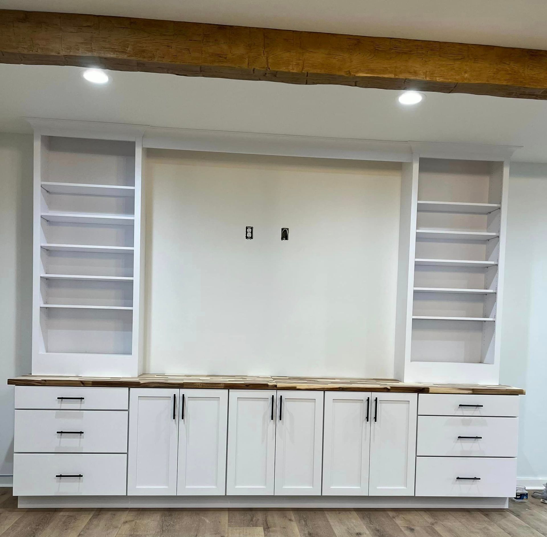 A kitchen with white cabinets , drawers , and shelves.
