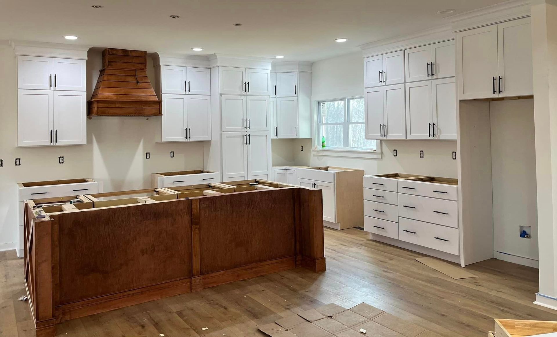 A kitchen with white cabinets and wooden floors is being remodeled.