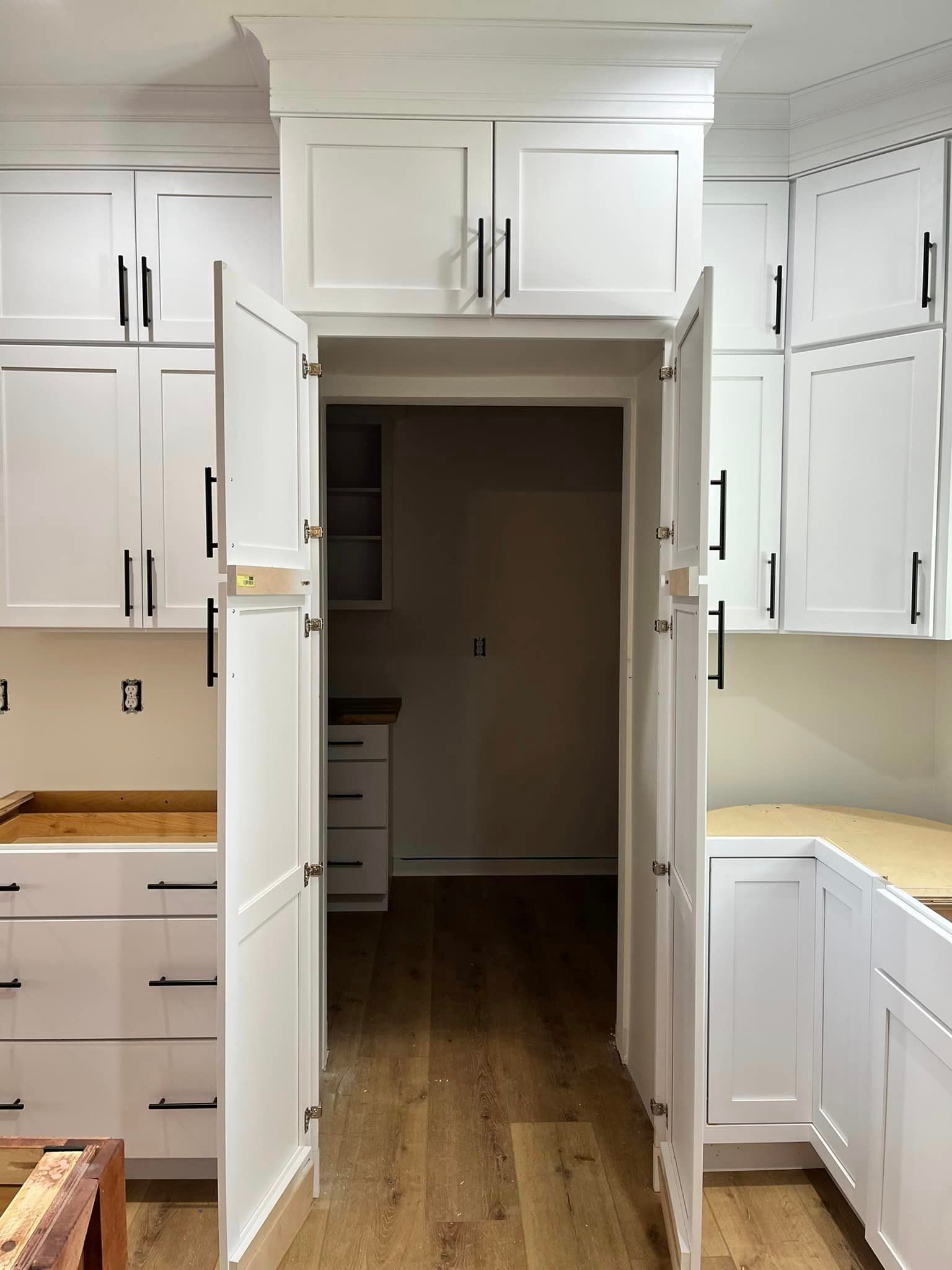 A kitchen with white cabinets and wooden floors