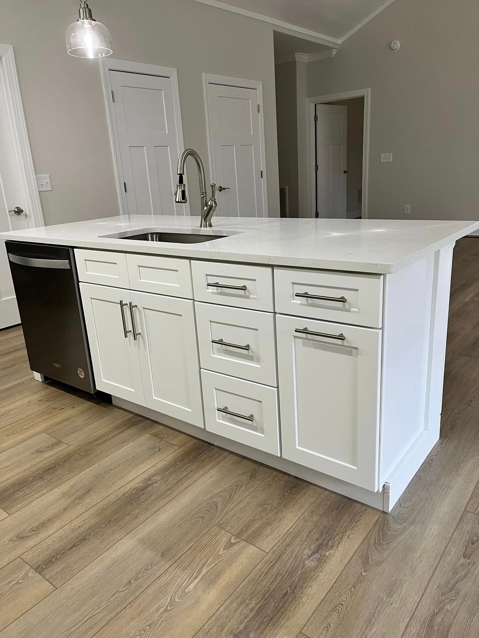 A kitchen with white cabinets , a sink , and a dishwasher.