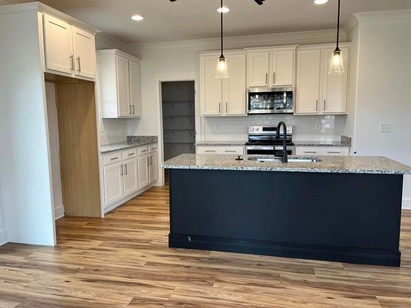 A kitchen with white cabinets and a black island.