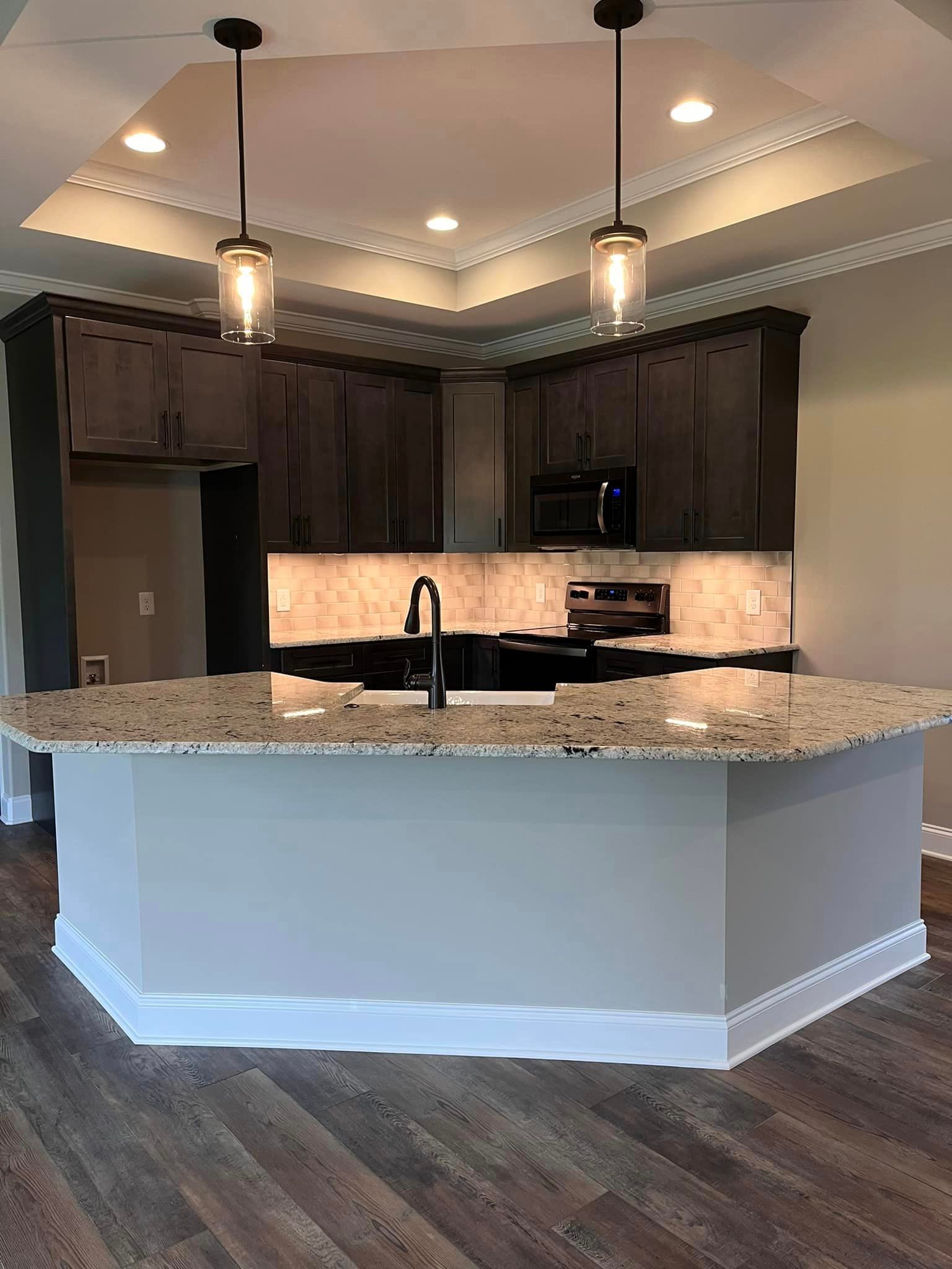 A kitchen with a large island and granite counter tops.