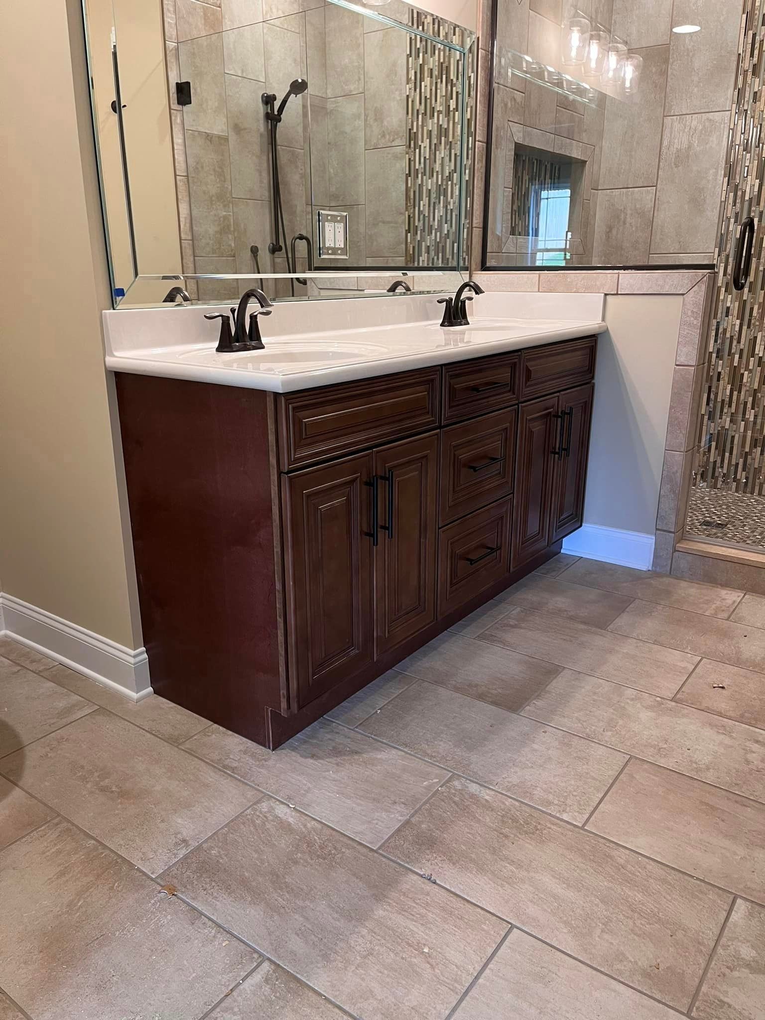 A bathroom with two sinks and a walk in shower.
