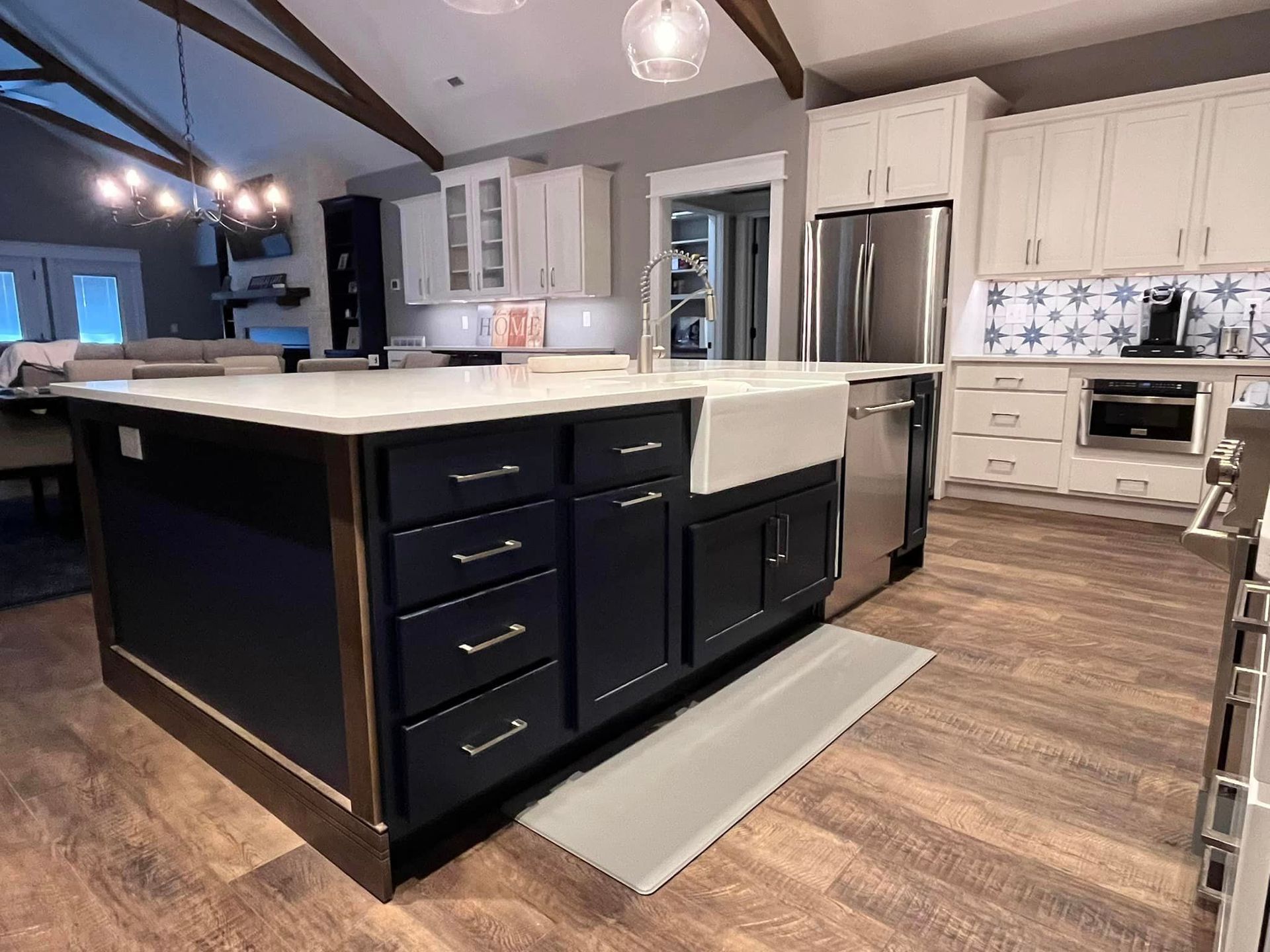 A kitchen with black cabinets , white cabinets , stainless steel appliances and a large island.