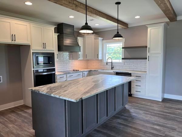 A kitchen with white cabinets and a large island in the middle.
