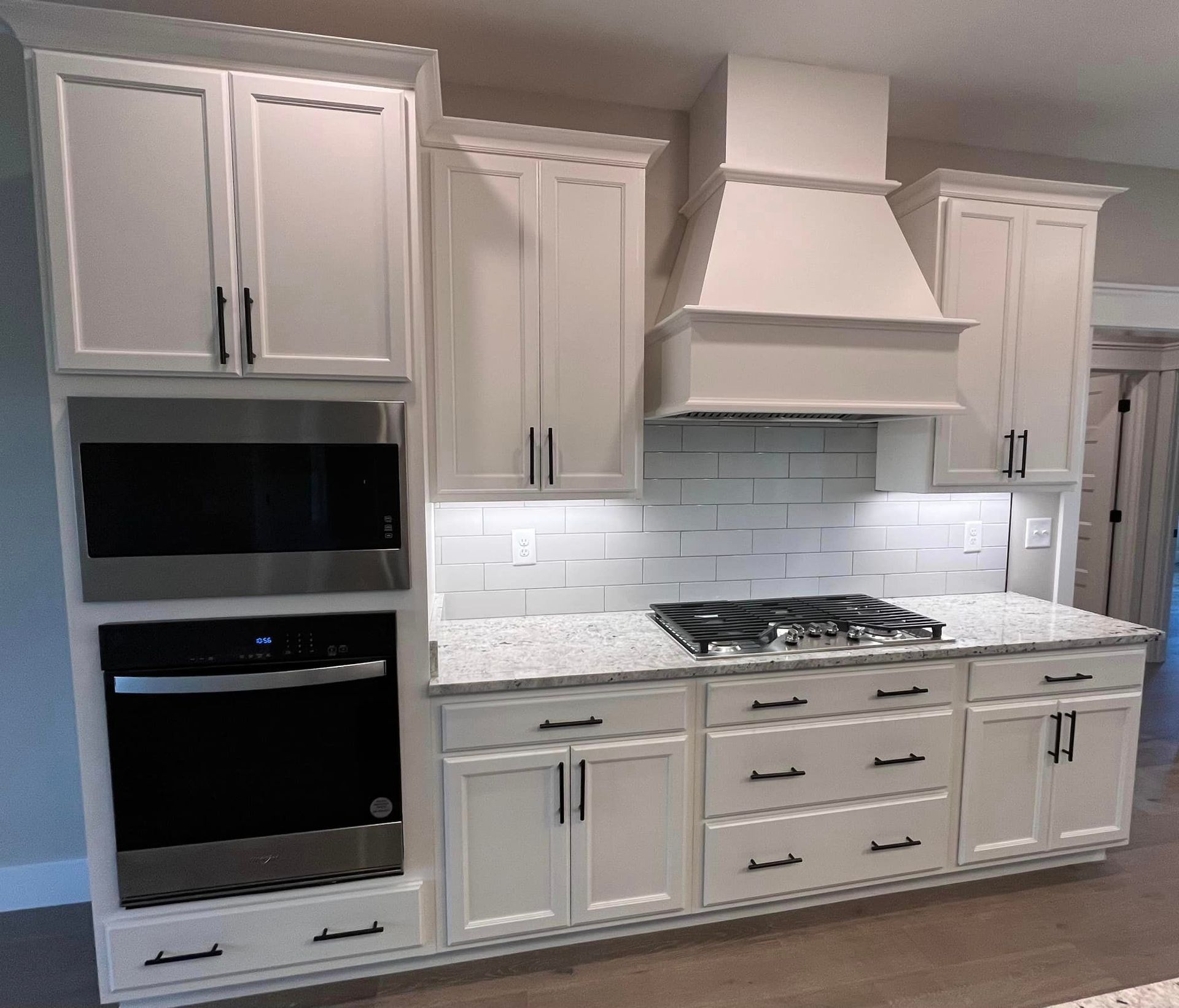 A kitchen with white cabinets , a stove top oven , and a microwave.