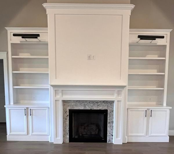 A living room with a fireplace , shelves and cabinets.