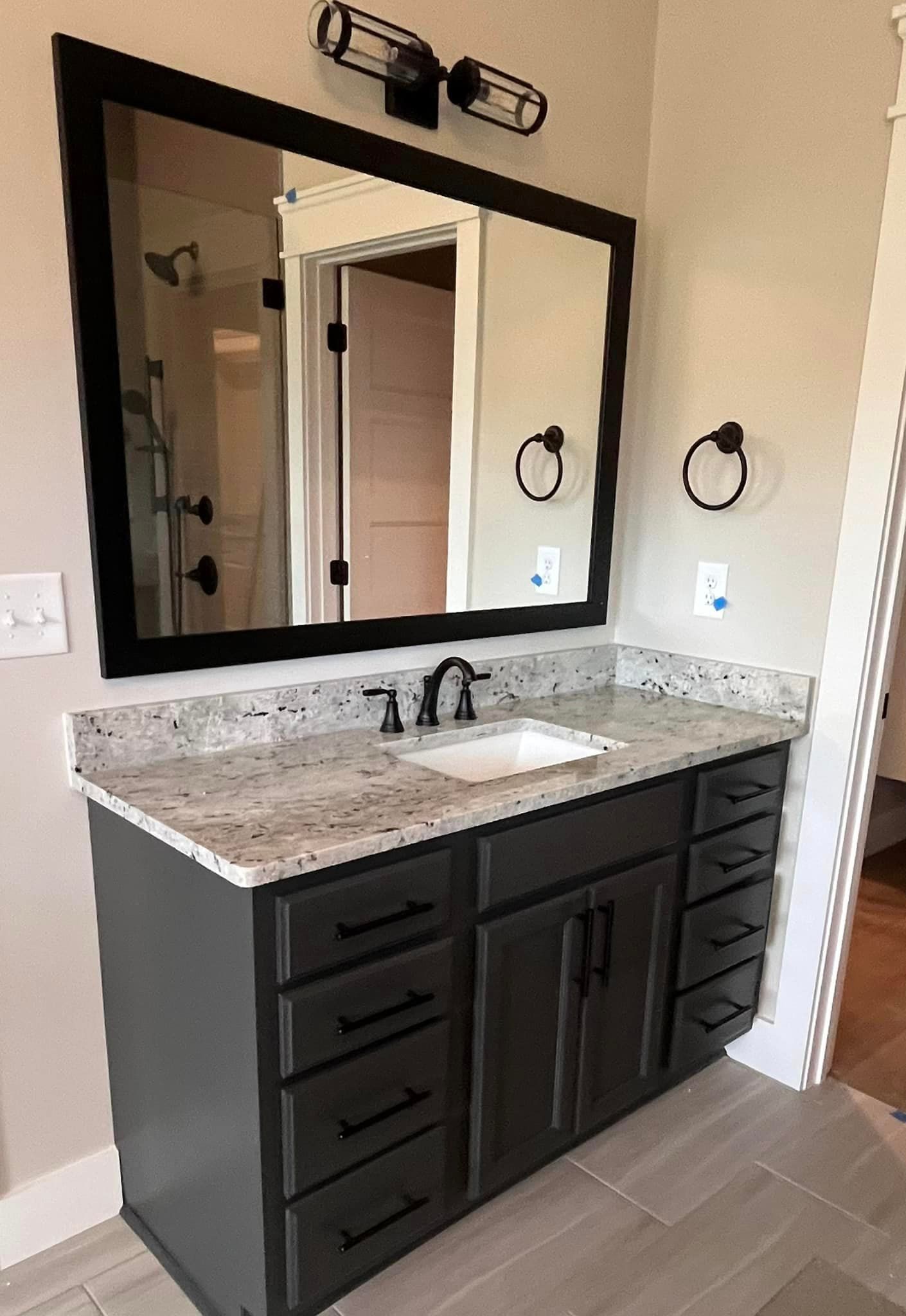 A bathroom with a sink , mirror and cabinets.