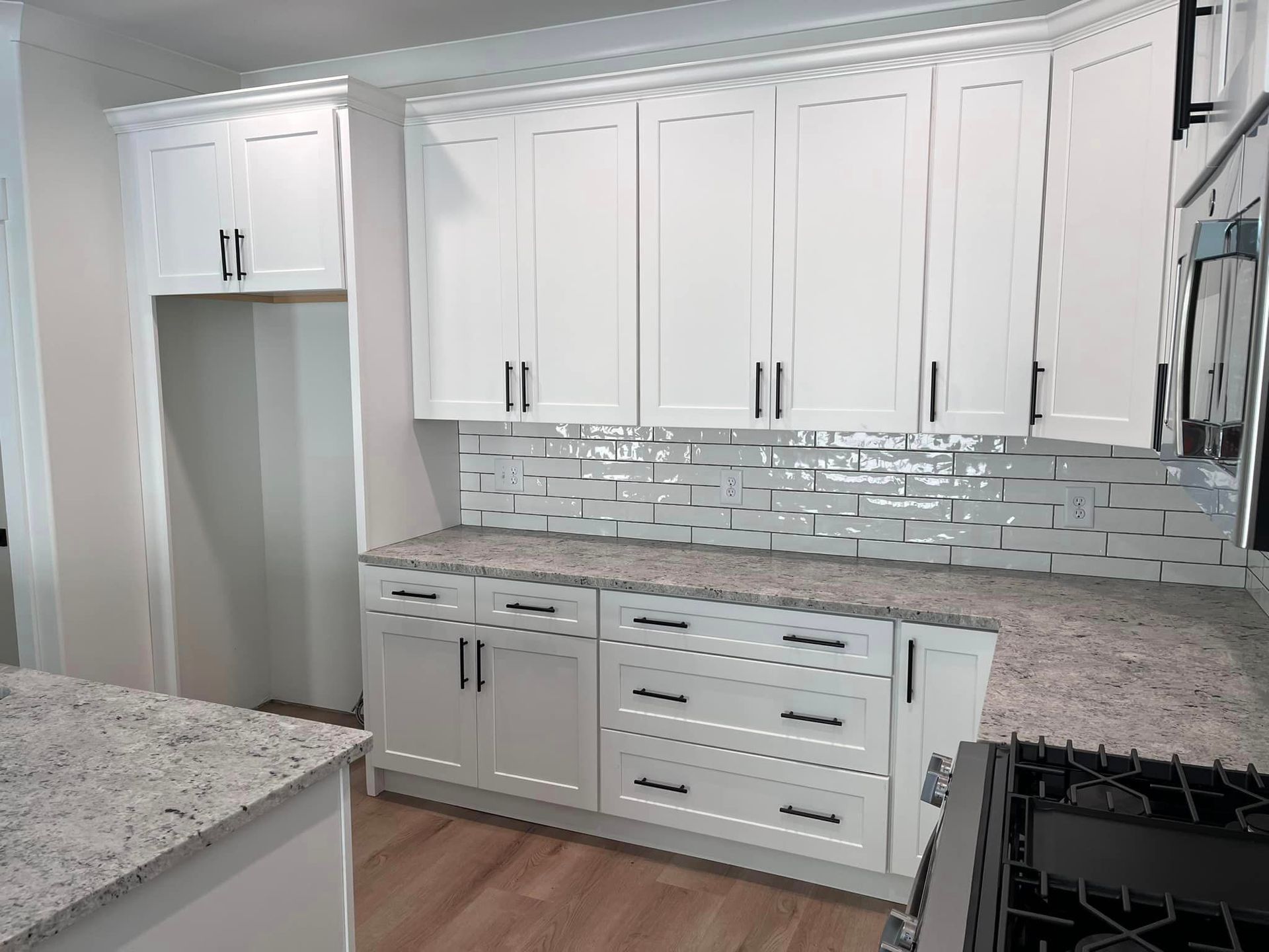 A kitchen with white cabinets and granite counter tops.