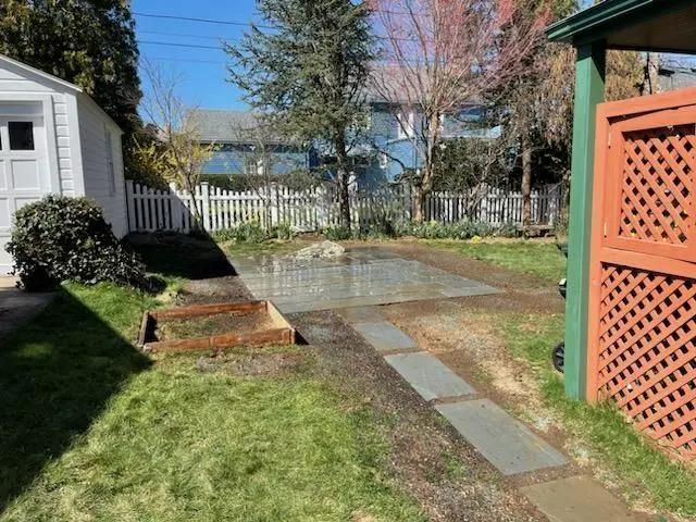 Backyard with grass, concrete path, and patio. 