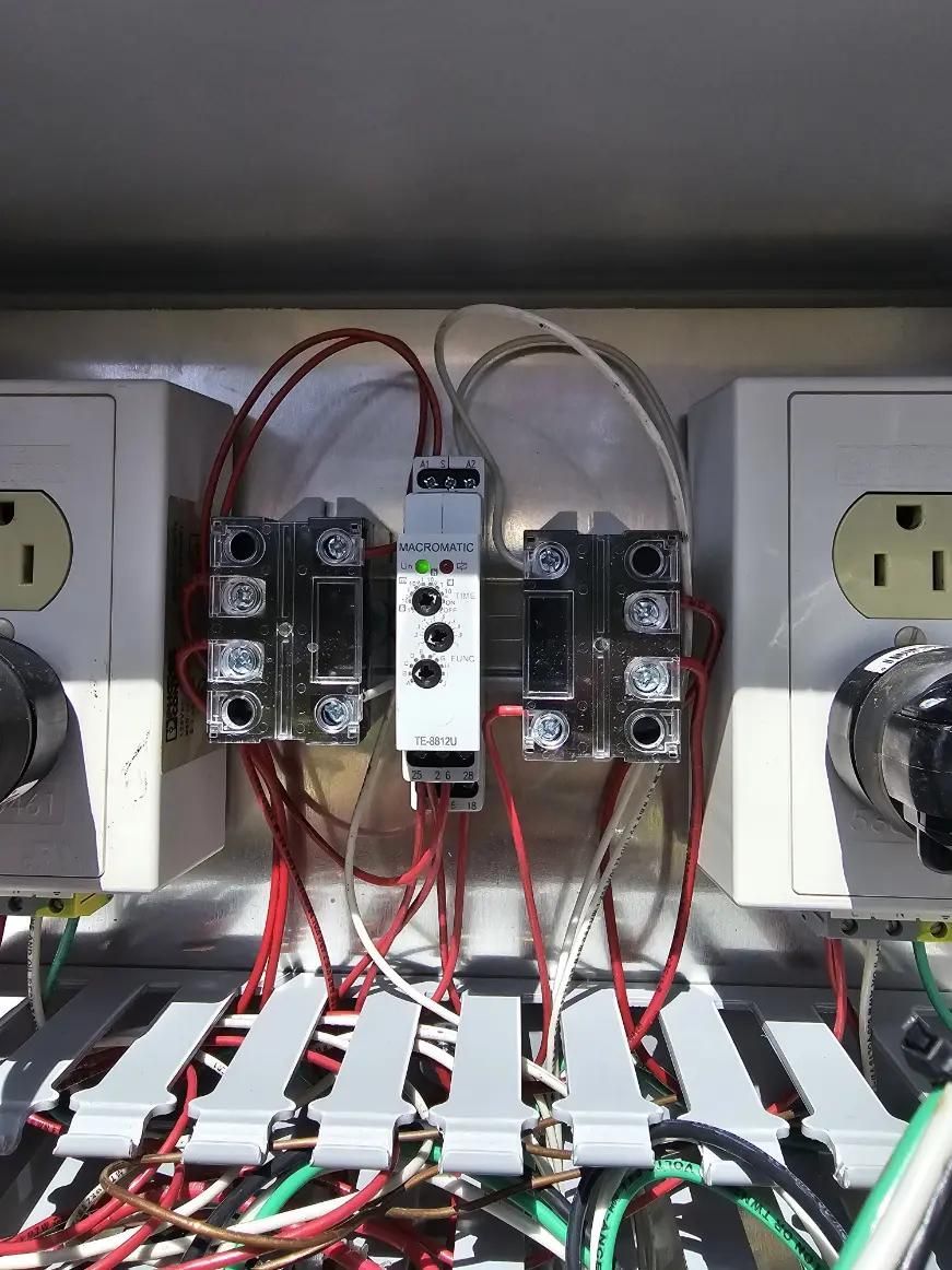 Electrical panel with red and white wires connected to relays, outlets, and a safety module.