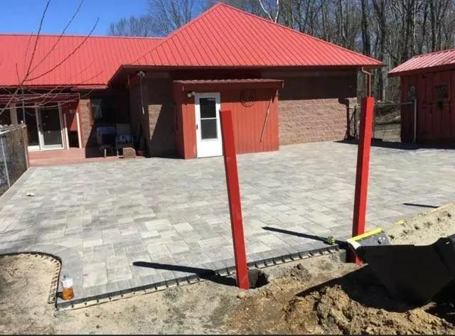 Brick building with red roof and pavement with two red posts.