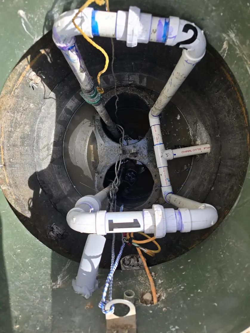 Overhead view inside a dark well with white PVC pipes forming a distribution system. 