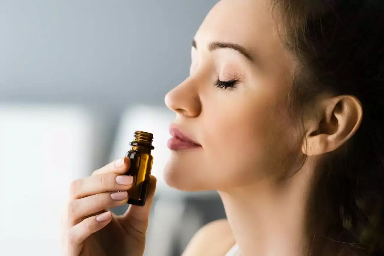Woman smelling diffuser oil bottle