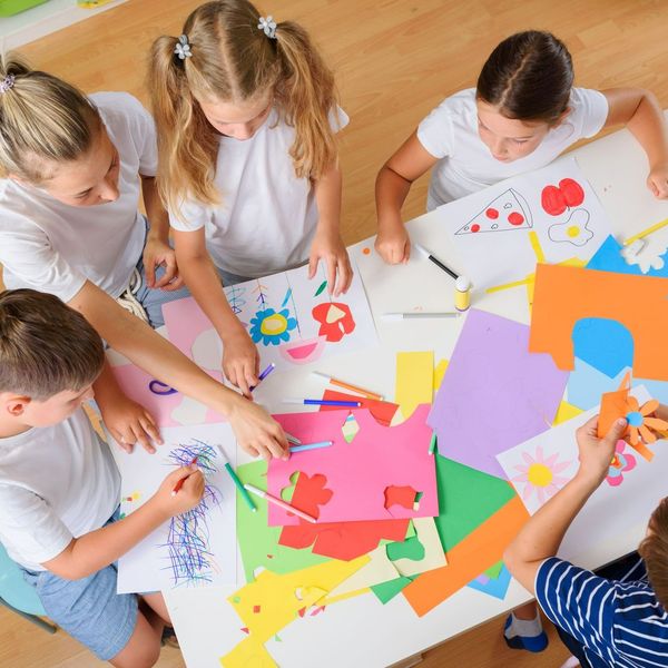 A group of children are sitting around a table making crafts.