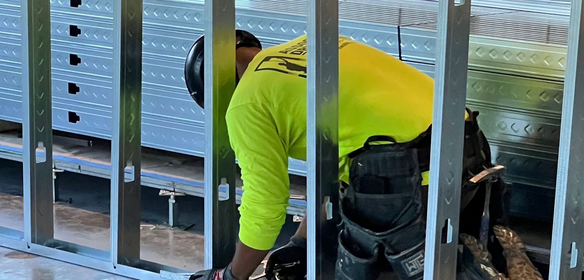 A man in a yellow shirt is working on a wall.