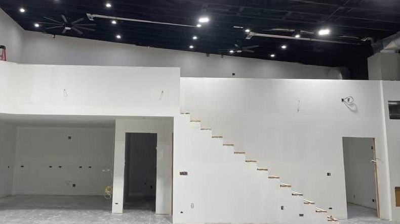 A large empty room with stairs leading up to the second floor.