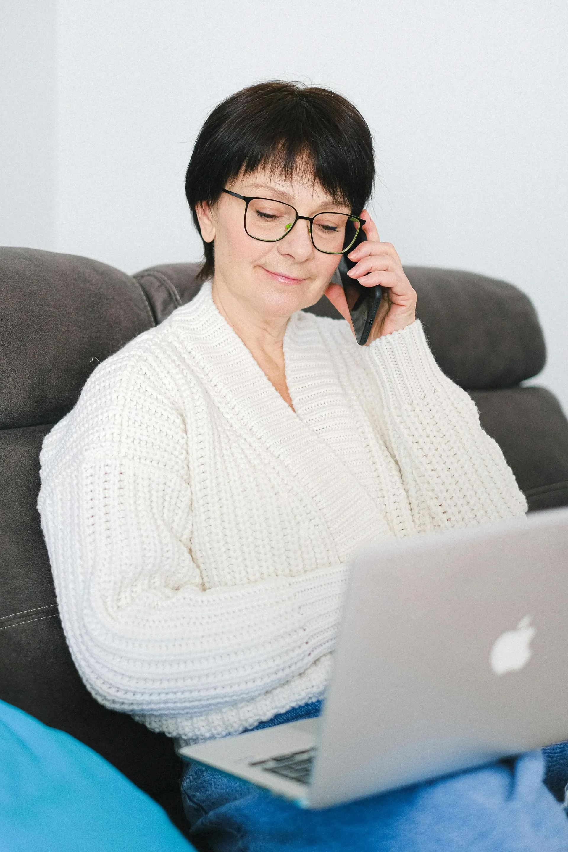 Women Sitting with a open laptop, Speaking on Her Phone.