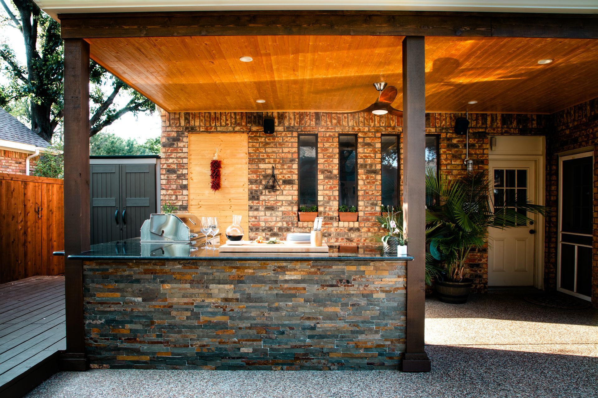 Outdoor bar with stone facade, under a wooden roof. Brick wall backdrop, patio and deck.