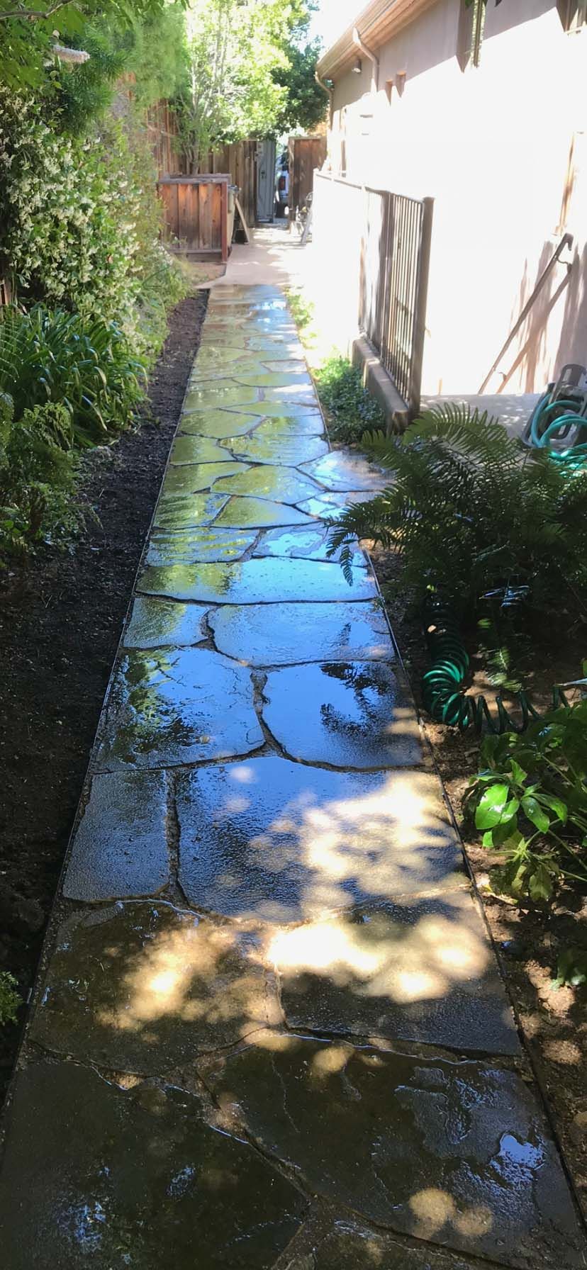 Stone front porch and steps leading to a house with a red door. Landscaping with flowers.