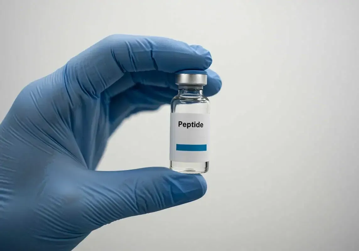 Gloved hand holding a vial labeled