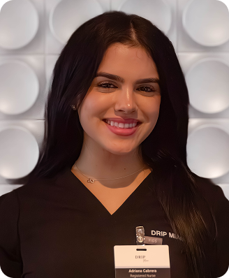 Woman with dark hair wearing black scrubs smiles, ID badge visible.