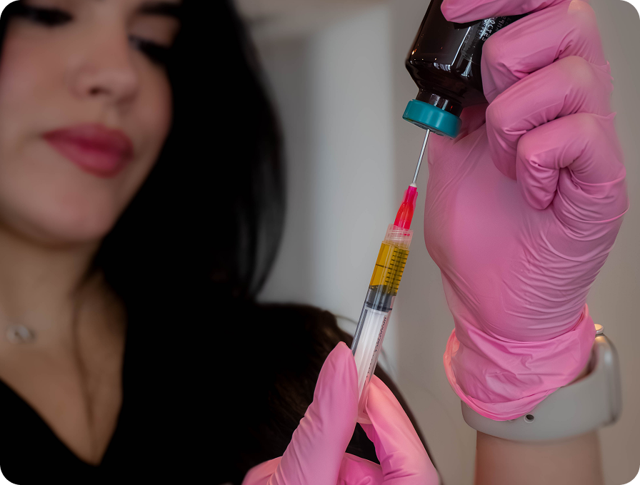 Person in pink gloves filling syringe from vial; medical procedure.